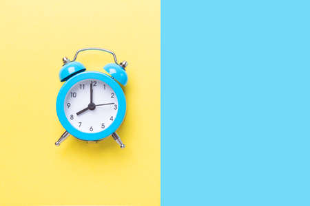 Blue alarm clock on two tone color yellow and blue background. Top view, place for text - Imageの写真素材