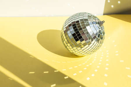 Shining disco ball on yellow background. Disco ball with bright rays - Imageの写真素材