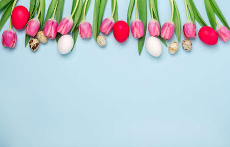 Spring background with multicolored easter eggs, tulips and hyacinths on blue. Easter concept. Copy...