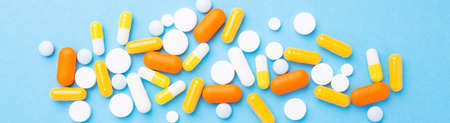 Multicolor tablets and pills capsules on blue background Heap of assorted various medicine tablets...