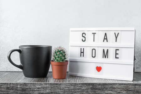 Lightbox with text STAY HOME, mug and cactus plants on wooden table. Stay safe, stay inside home concept - Imageの写真素材