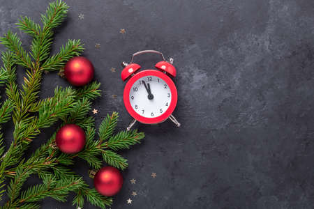 Christmas banner with fir tree, holly and red alarm clock on dark stone background. Top view Copy space - Imageの写真素材