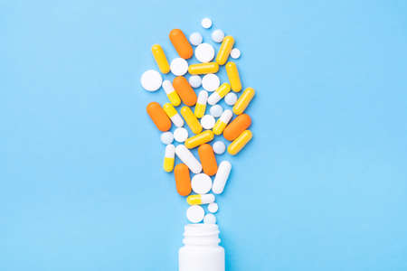 Heap of pills and capsules spilling out of a plastic bottle. Top view - Imageの写真素材