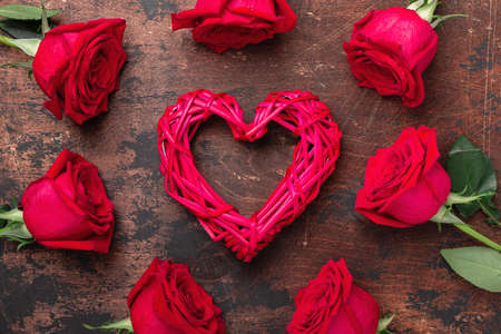 Valentines day greeting card with red roses and decorative heart on wooden background. Top view - Imageの写真素材