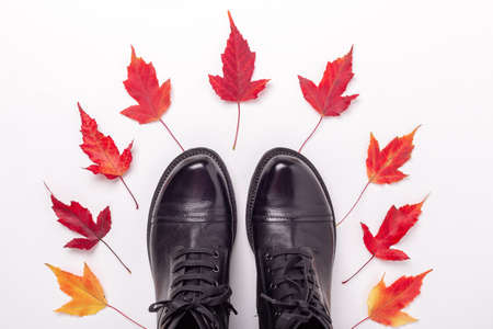 Black leather boots and red leaves on white background. Autumn sale concept. Top view - Image