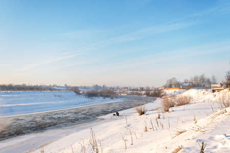 Winter snow river landscape. Rural scene. Ice floats on the river. Steam escaping over the frozen...