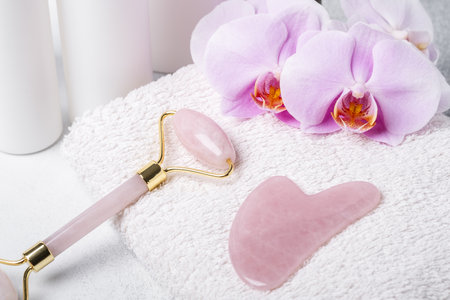 Gua Sha massager and face roller on stone background. Massage tool for facial skin care, SPA beauty treatment concept.の写真素材