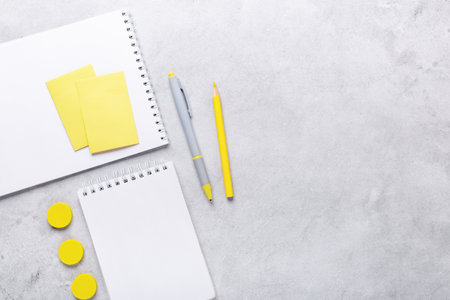 Office workplace with notepad and stationery accessories on gray stone background. Yellow stationery. Flat lay. Top view - Imageの写真素材
