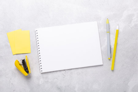 Gray workspace with notepad and yellow stationery accessories. Illuminating Yellow and Ultimate...