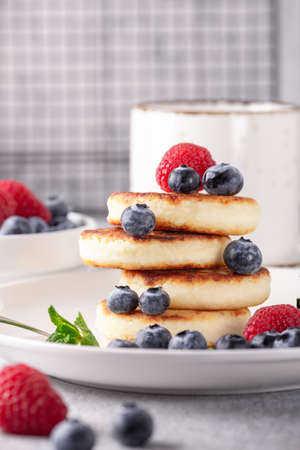 Stack of cheese pancakes with fresh berries, cup of coffee on the table. Tasty breakfast food....