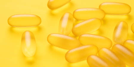 Close up Omega 3 capsules on yellow background. Fish oil softgels - Image