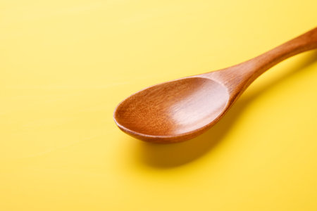 Empty wooden spoon on yellow background - Imageの写真素材