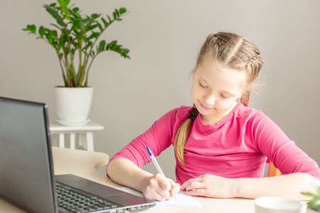 Schoolgirl studying at home using laptop. Home school, online education, home education, quarantine...