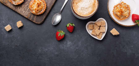 Cup of coffee, cakes and strawberries on a wooden cutting board on dark stone background. Horizontal banner. Top view - Imageの写真素材