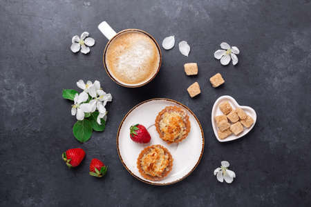 Cup of coffee with cakes and spring flowers on dark stone background. Top view. Imageの写真素材