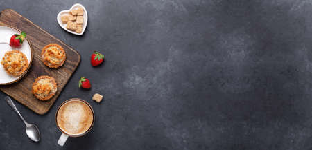 Cup of coffee, cakes and strawberries on a wooden cutting board on dark stone background. Horizontal banner. Top view - Imageの写真素材