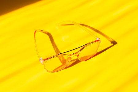 Fashionable pink sunglasses on yellow background. Concept of summerの写真素材
