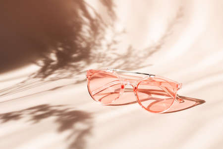 Fashionable pink sunglasses on floral background. Pampas grass natural shadows on beige background. Concept of summerの写真素材