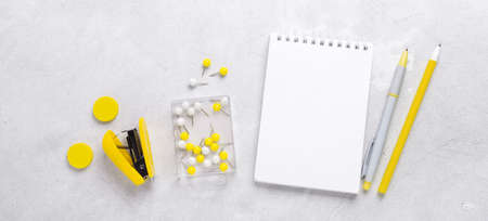 Horizontal banner. Office workplace. Notepad with pen and yellow sticker on gray stone background. Flat lay. Top viewの写真素材