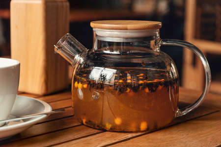 Tea with sea buckthorn in glass teapot in cafe. Healthy and delicious sea buckthorn tea