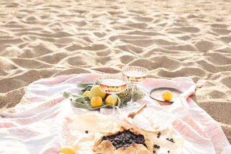 Beautiful summer picnic at sunset on beach with rose wine, cheese, blueberry galette and fresh fruits. Copy spaceの写真素材