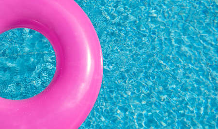 Summer banner with pink inflatable ring in blue swimming pool, surface with waves, textured water. Top view. Copy spaceの写真素材