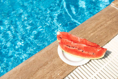 Fresh watermelon on border of swimming pool. Hot summer travel, vacation and holiday concept. Top view. Copy spaceの写真素材