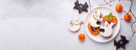 Halloween gingerbread cookies on white plate on stone background. Bright homemade cookies for Halloween party. Copy spaceの写真素材