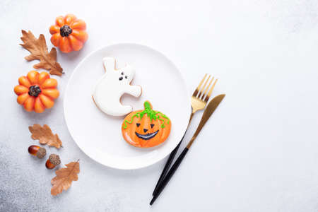 Halloween table setting with gingerbread cookies on white plate and cuterly on white background. Bright homemade cookies for Halloween partyの写真素材
