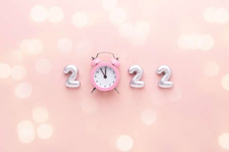New year composition with silver numbers 2022 and alarm clock on pink background. Bokeh effect. Happy New Year conceptsの写真素材