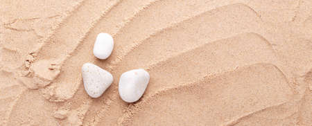 White stones on the sand background. Top view