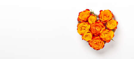 Horizontal banner. Orange rose flowers in heart shape bowl on white background. Valentines day concept. Flat lay, top view, copy spaceの写真素材