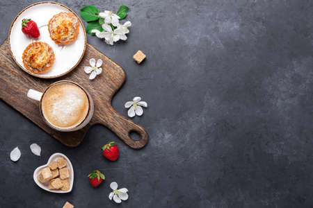 Delicious cake, coffee, fresh berry and spring flowers on dark stone background. Top view. Copy...