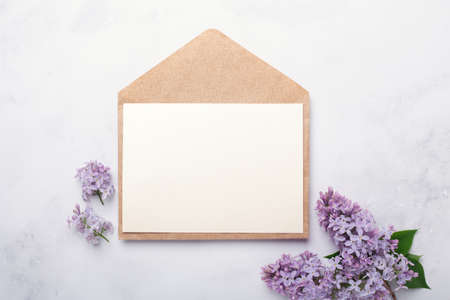 Flowers composition. Envelope, sheet of paper and lilac flowers and on stone background. Template for your invitation or greeting card. Flat lay, top viewの写真素材