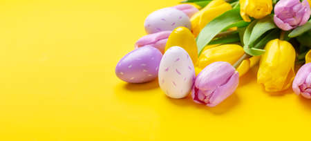Easter composition. Multicolored easter eggs and tulips on yellow background. Easter concept. Copy spaceの写真素材