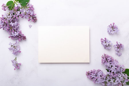 Flowers composition. Sheet of paper and lilac flowers on stone background. Template for your invitation or greeting card. Flat lay, top viewの写真素材