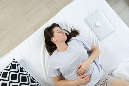 Young woman in headphones sleeping on the bed. View from aboveの写真素材