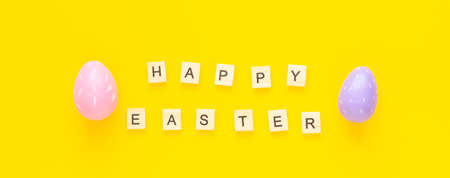 Greeting card with text HAPPY EASTER. Multicolored easter eggs and paper rabbits on yellow backgroundの写真素材