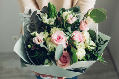Woman holding fresh blossoming flower bouquet of beautiful flowers in pastel pink colourの写真素材