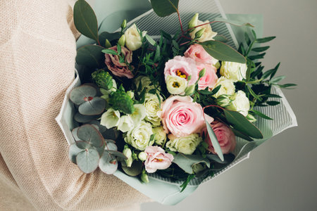 Woman holding fresh blossoming flower bouquet of beautiful flowers in pastel pink colourの写真素材