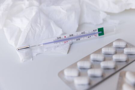 The thermometer and pills, used napkins around on white table