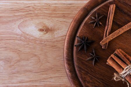 Three stars of star anise, cinnamon separately and in a bunch lie on a dark brown wooden board, on a light brown board. Great background for a cafe or restaurant menuの写真素材