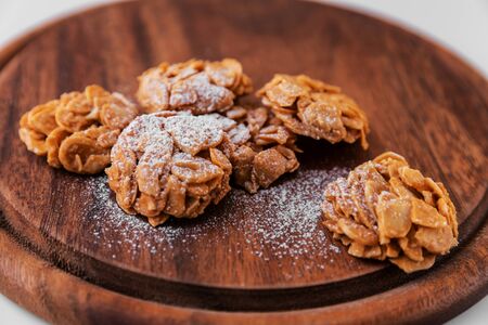 Almond cookies sprinkled with icing sugar on top on a dark brown wooden board on a white background....