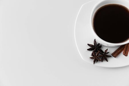 Part of white cup with coffee and saucer, with three star anise star anise and cinnamon sticks, on a white background. A good idea for the menu or sign of a restaurant or cafe, cafeteriaの写真素材