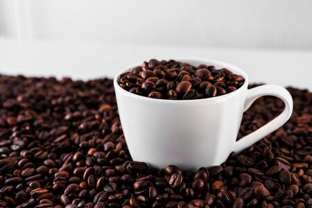 White mug with roasted coffee beans everywhere, inside the mug and a lot around it with white background. Great for going to a cafe, restaurant, cafeteria menu or as a sign
の写真素材