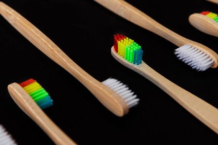 Group of white and rainbow eco bamboo toothbrushes, on black background. Top view. Natural organic product for oral hygiene. Dental zero waste and no plastic concept. Safe for the earth. の写真素材