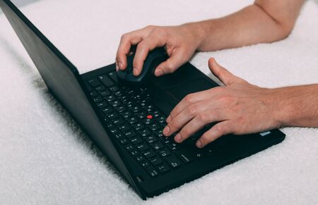 Men's hands are typing on a black laptop with computer mouse. Stay home concept. Order products...