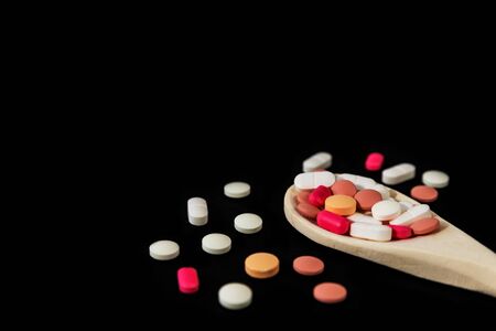 Mixed medicine pills, tablets on wooden spoon on dark background. Many different pills. Health care. Top view. Space for text. Copy space. New image. Closeup. Soft focus. Flatlayの写真素材