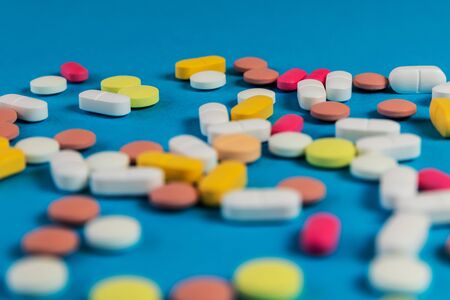 Different medicine pills, tablets on blue background. Many medicine pills and tablets with place for...