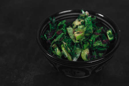 Bowl with salad of organic vegetables and herbs on dark textured background. Top View, space for text. Organic eco food. Carrots with green tops tied with rope. Healthy diet. Freshly cut vegetablesの写真素材